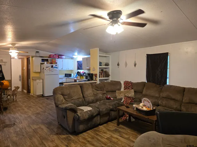 a living room with furniture kitchen view and a chandelier