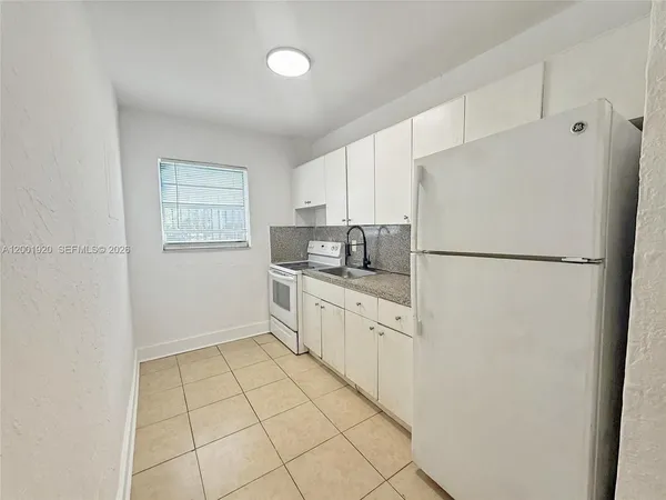 a kitchen with white cabinets and refrigerator