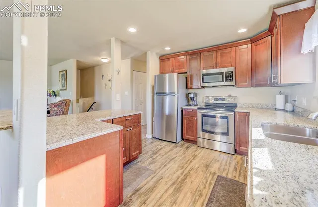 a kitchen with stainless steel appliances granite countertop a sink stove refrigerator and cabinets