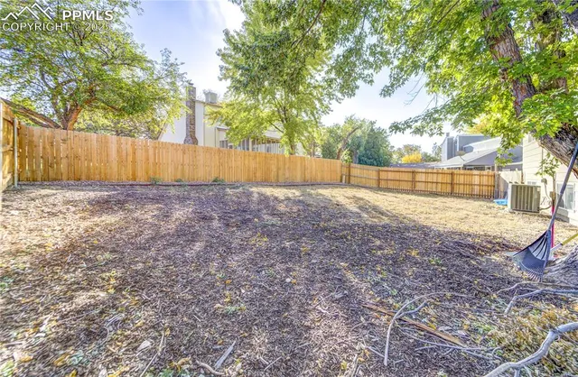 a view of backyard with tree and wooden fence