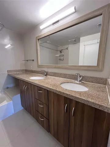 a bathroom with a granite countertop double sink and a mirror