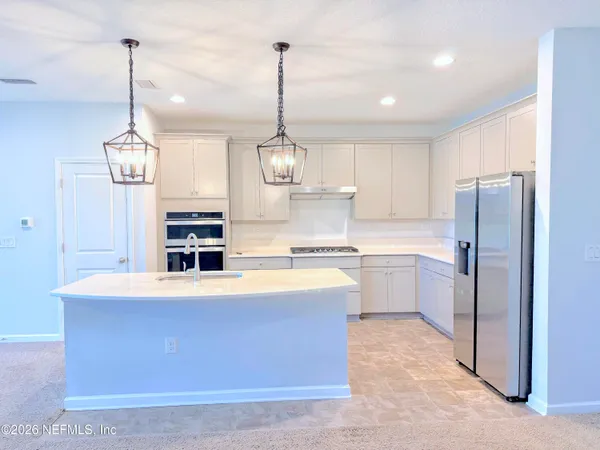 a large kitchen with stainless steel appliances kitchen island granite countertop a sink and a refrigerator