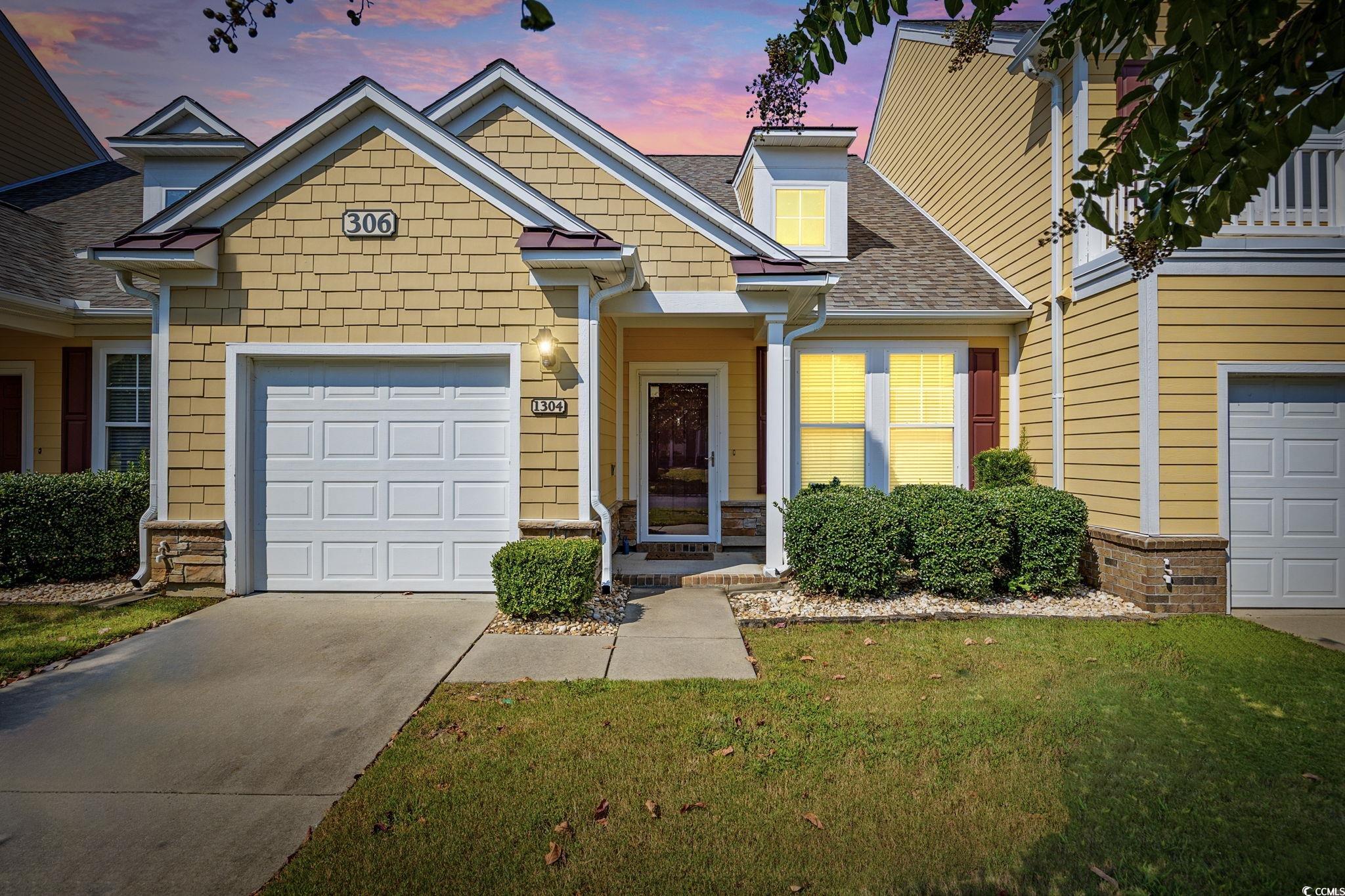 View of front of property with a shingled roof, concrete driveway, and a lawn