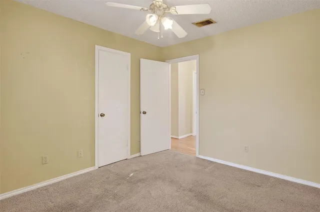 an empty room with windows and fan