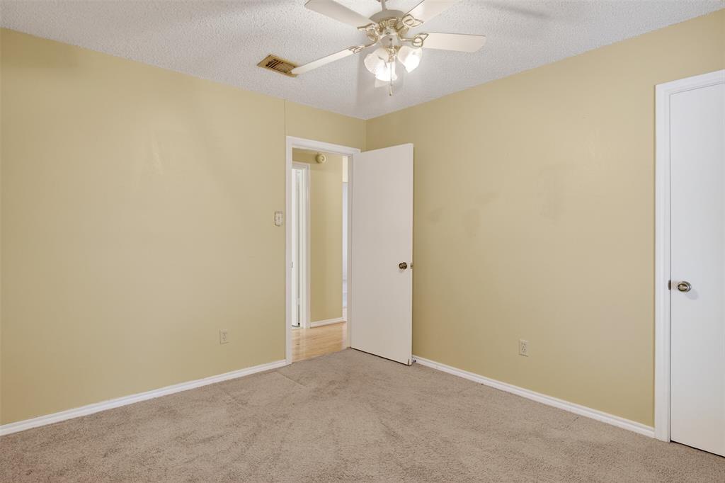 6946 Trailcrest Drive Dallas, TX 75232 - Photo 18 of 22 an empty room with a chandelier fan and a bathroom