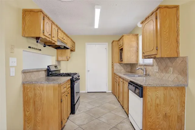 a kitchen with granite countertop a sink stove and cabinets