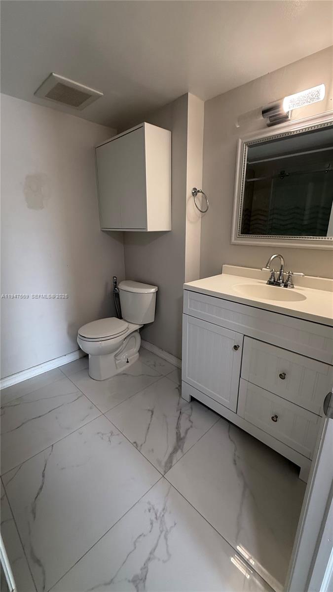 17600 Northwest 68th Avenue, Unit B2002 Hialeah, FL 33015 - Photo 14 of 38 a bathroom with a toilet sink and mirror