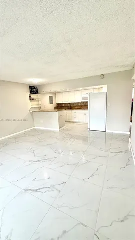 a kitchen with granite countertop a stove a oven and white cabinets with wooden floor