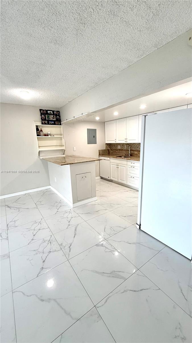 17600 Northwest 68th Avenue, Unit B2002 Hialeah, FL 33015 - Photo 4 of 38 a kitchen with granite countertop a stove a oven and white cabinets with wooden floor
