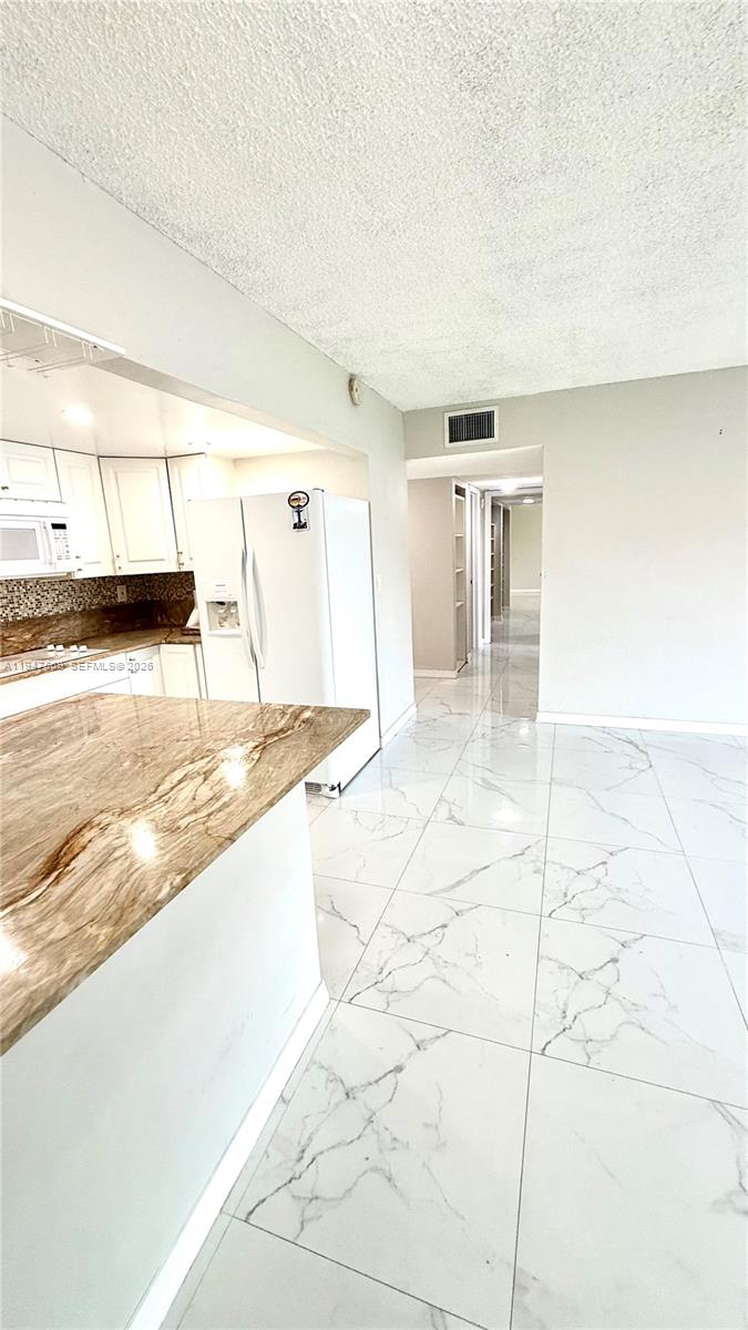 17600 Northwest 68th Avenue, Unit B2002 Hialeah, FL 33015 - Photo 5 of 38 a view of a kitchen with kitchen island white cabinetry and black appliances