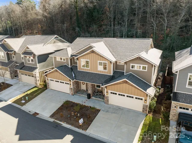 an aerial view of a residential houses with yard and mountain view in back