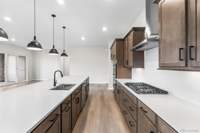 a kitchen with kitchen island stainless steel appliances a sink a stove and a wooden floor
