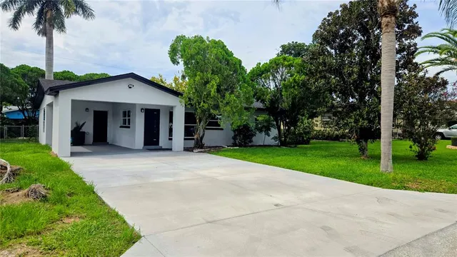a view of a house with a yard and palm trees