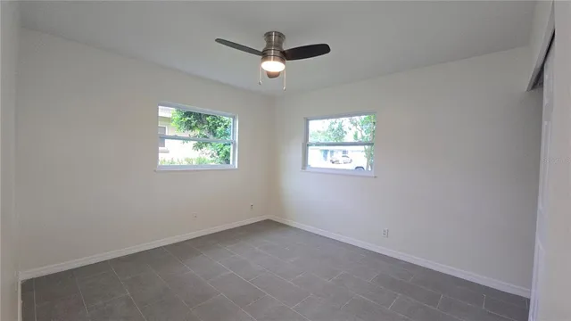 an empty room with windows and ceiling fan