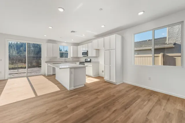 a kitchen with stainless steel appliances granite countertop a refrigerator sink and white cabinets