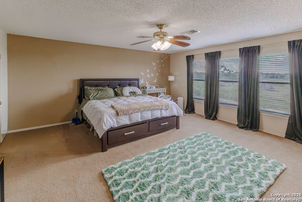 744 County Road 2651 Rio Medina, TX 78066 - Photo 13 of 27 a spacious bedroom with a bed and a chandelier