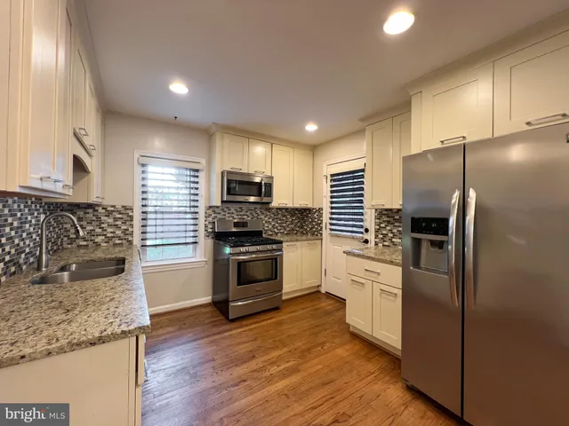 a kitchen with granite countertop a refrigerator and a stove top oven