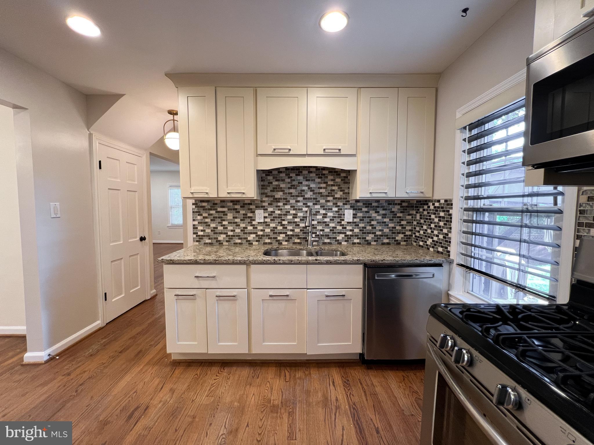 10159 Sutherland Road Silver Spring, MD 20901 - Photo 15 of 30 a kitchen with stainless steel appliances granite countertop a stove and a wooden floor