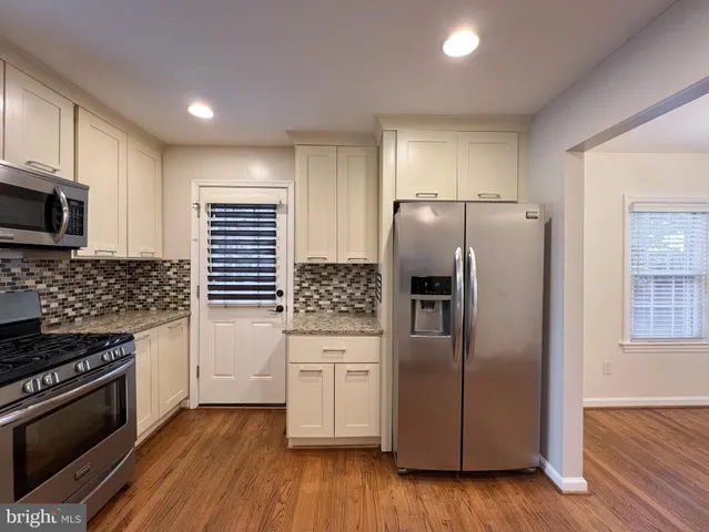 a kitchen with granite countertop a refrigerator and a stove top oven