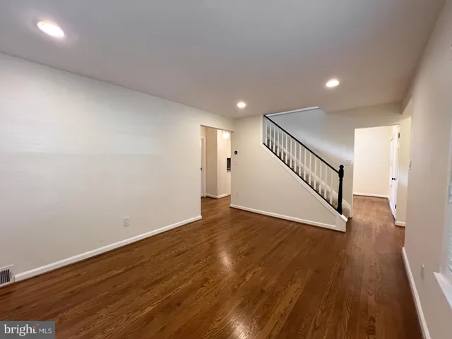 a view of an empty room with wooden floor and stairs