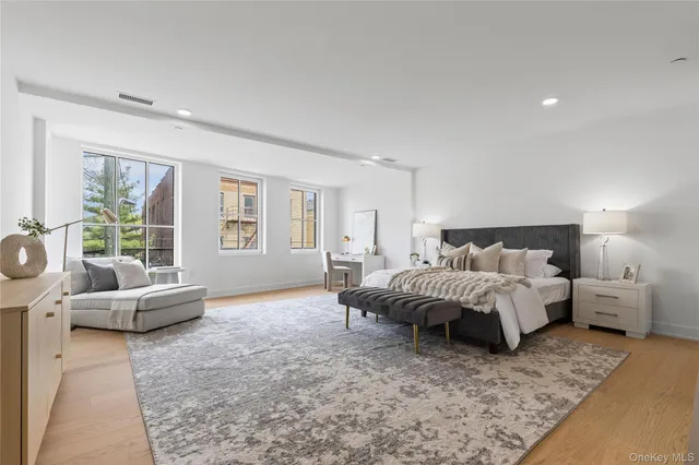 a spacious bedroom with a bed a couch and large window