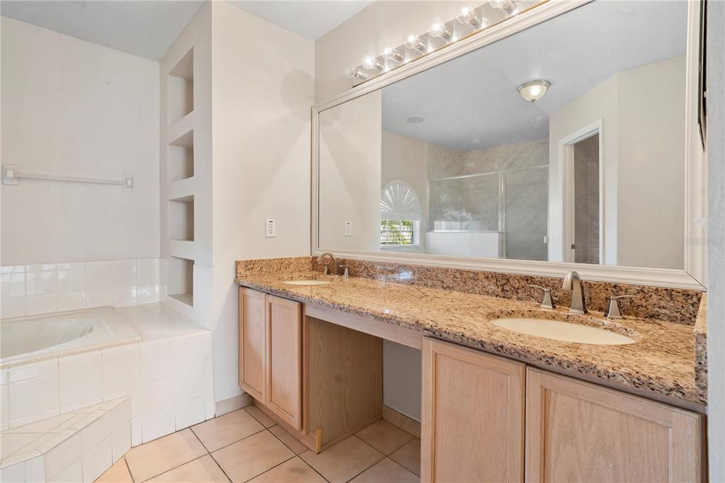 565 Pinehurst Cove Kissimmee, FL 34758 - Photo 19 of 36 a bathroom with a granite countertop bathtub a sink and a mirror