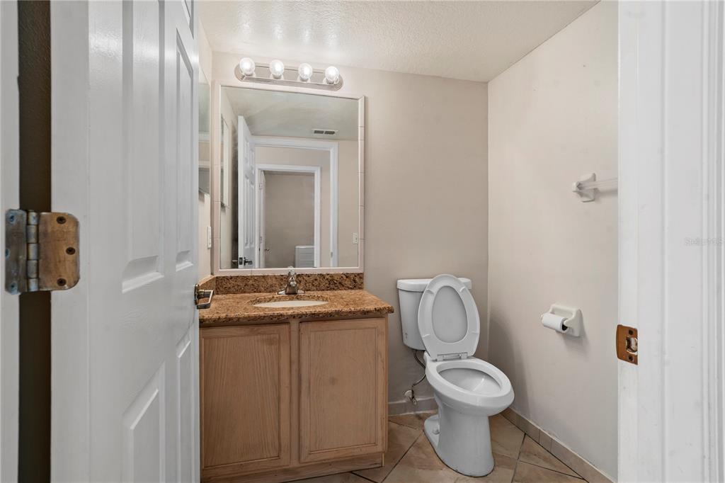 565 Pinehurst Cove Kissimmee, FL 34758 - Photo 25 of 36 a bathroom with a granite countertop toilet and a sink