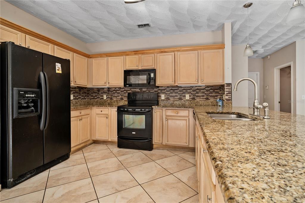 565 Pinehurst Cove Kissimmee, FL 34758 - Photo 28 of 36 a kitchen with stainless steel appliances granite countertop a refrigerator sink and stove