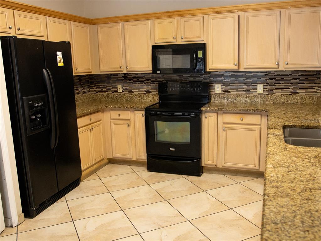565 Pinehurst Cove Kissimmee, FL 34758 - Photo 3 of 36 a kitchen with stainless steel appliances granite countertop a refrigerator stove and microwave
