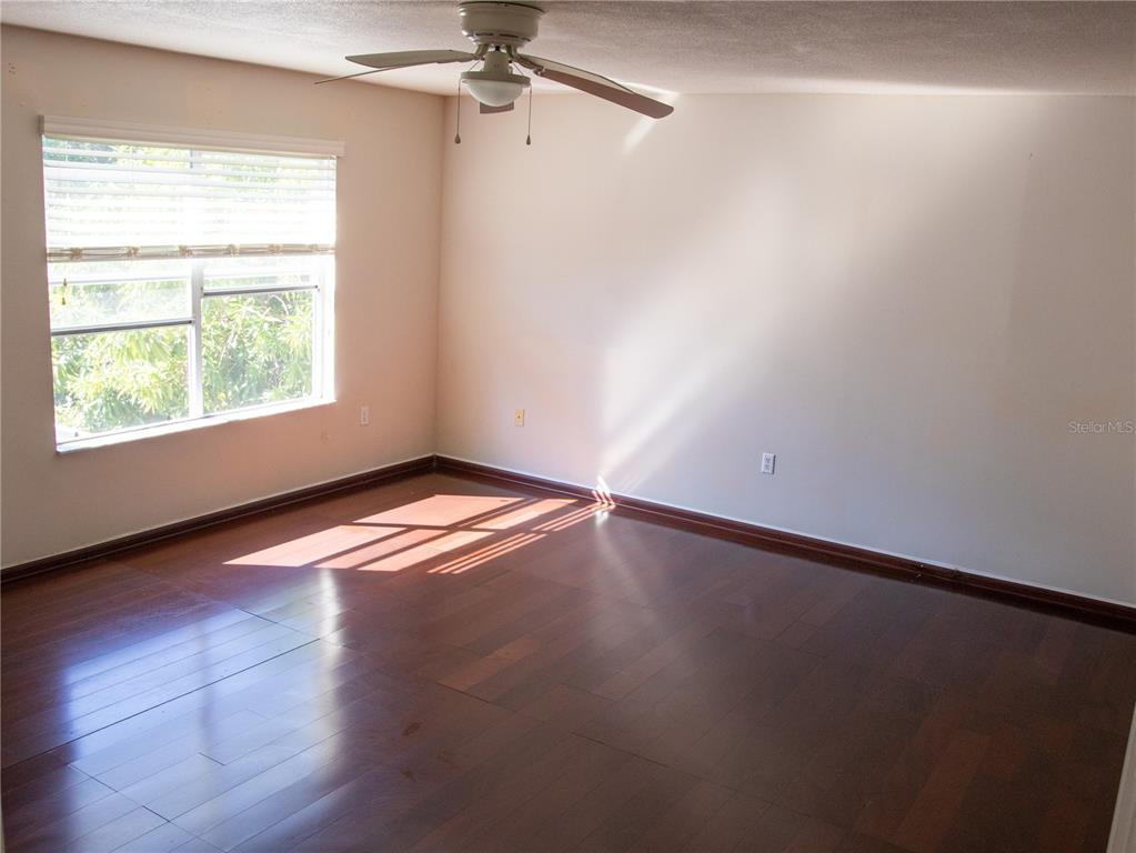 565 Pinehurst Cove Kissimmee, FL 34758 - Photo 6 of 36 an empty room with wooden floor chandelier fan and windows