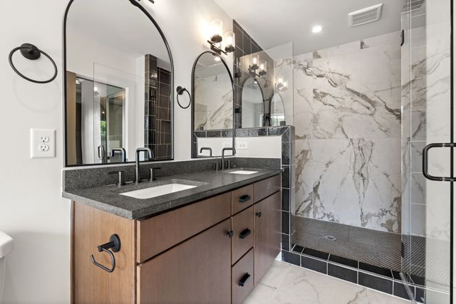 a bathroom with a granite countertop sink a mirror and a shower