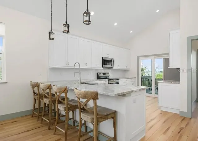 a kitchen with stainless steel appliances kitchen island granite countertop a stove a sink a dining table and chairs with wooden floor