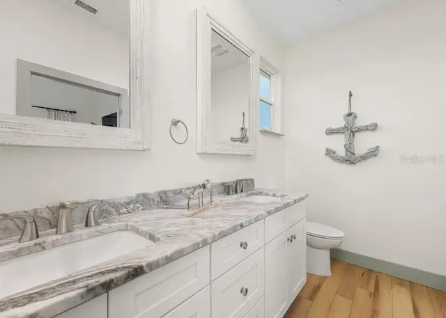 a bathroom with a granite countertop sink a toilet and mirror