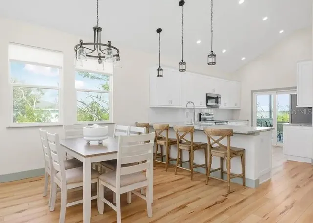 a dining room with wooden floor a chandelier a wooden table and chairs