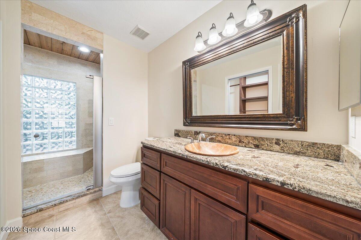 189 Abeto Terrace Sebastian, FL 32958 - Photo 18 of 38 a bathroom with a granite countertop sink a toilet a mirror and shower