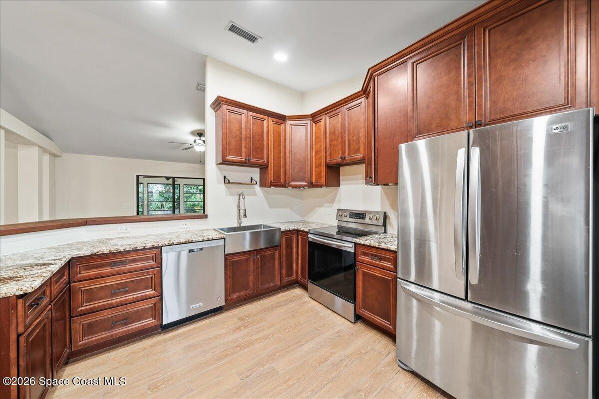 189 Abeto Terrace Sebastian, FL 32958 - Photo 9 of 38 a kitchen with stainless steel appliances granite countertop a refrigerator a sink dishwasher a stove with wooden cabinets and floor