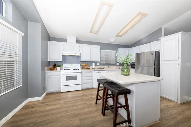 a kitchen with stainless steel appliances white cabinets and wooden floor