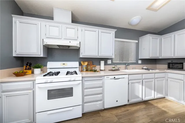a kitchen with granite countertop white cabinets and white appliances