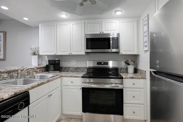 a kitchen with white cabinets stainless steel appliances and sink