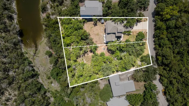 an aerial view of a house with pool and trees all around