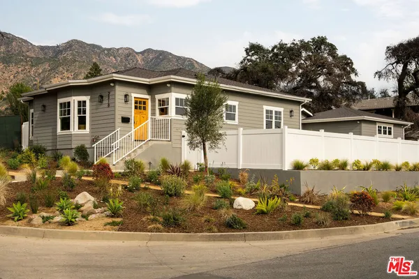 a view of a house with a yard and mountain view in back