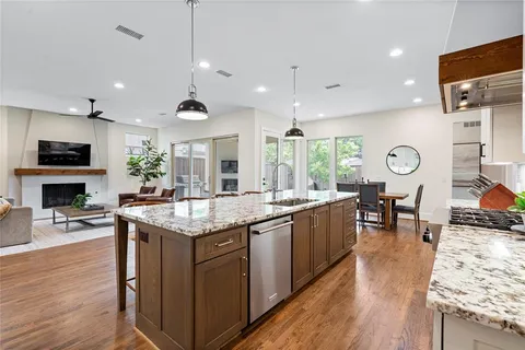a kitchen with granite countertop a stove a sink a dining table and chairs