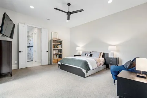 a spacious bedroom with a bed and a flat tv screen