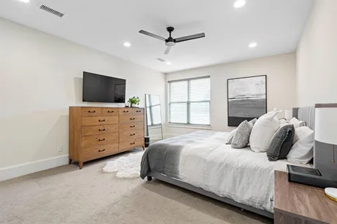 a bedroom with a bed a window and a flat screen television