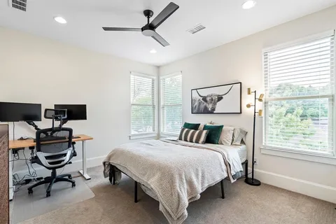 a bedroom with a bed a computer on the desk and a window