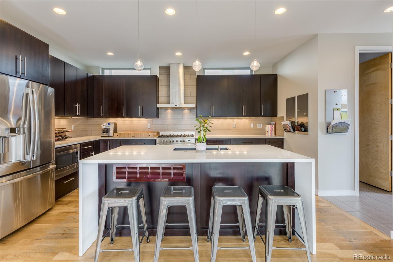 4030 Bryant Street Denver, CO 80211 - Photo 12 of 26 a kitchen with granite countertop a refrigerator and a stove top oven with wooden floor