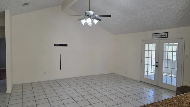 a view of an empty room with chandelier fan