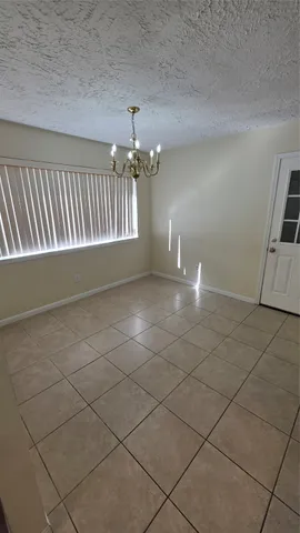 a view of an empty room with chandelier fan