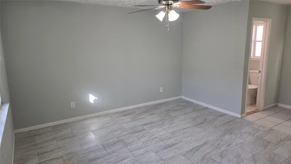 an empty room with wooden floor a ceiling fan and windows