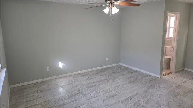an empty room with wooden floor a ceiling fan and windows